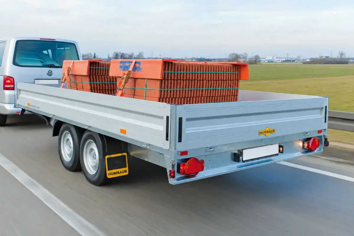 Zilverkleurige tandemasser met vastgezette lading achter een bestelbus